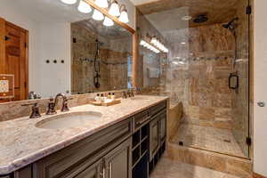 Bathroom with a stall shower, double vanity, and tile patterned floors