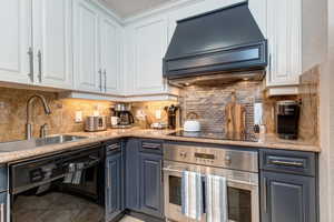 Kitchen with black appliances, custom range hood, a sink, and white cabinets