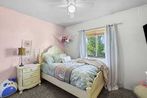 Bedroom with dark colored carpet and a ceiling fan