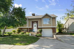 Split foyer home featuring brick siding, driveway, and an attached garage