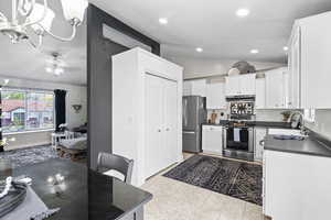 Kitchen featuring appliances with stainless steel finishes, a sink, dark countertops, lofted ceiling, and a chandelier