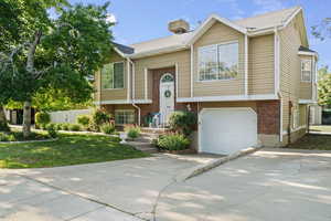 Split foyer home featuring driveway, brick siding, and a garage