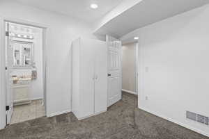 Unfurnished bedroom featuring carpet, baseboards, recessed lighting, and a sink