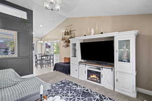 Living room with lofted ceiling, ceiling fan, a chandelier, and baseboards