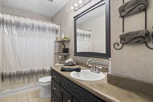 Bathroom with tile patterned flooring, toilet, vanity, and shower / tub combo with curtain