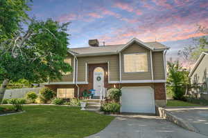 Split foyer home with brick siding, a garage, and concrete driveway