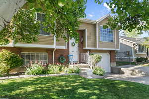 View of front facade featuring brick siding, a garage, a front lawn, and concrete driveway