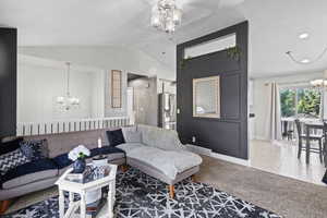 Carpeted living room featuring a chandelier, vaulted ceiling, baseboards, and tile patterned floors