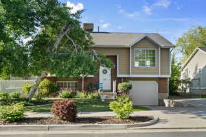 View of front facade with brick siding, fence, an attached garage, and driveway