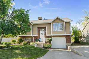 Split foyer home with brick siding, driveway, and a garage