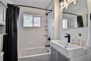 Bathroom featuring shower / bath combination with curtain, vanity, toilet