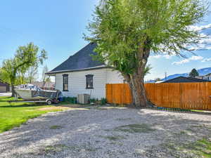View of side of property featuring central air condition unit, a detached garage, and gravel driveway