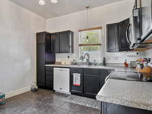 Kitchen with appliances with stainless steel finishes, a sink, pendant lighting, and light countertops
