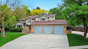 View of front of house featuring driveway, an attached garage, roof with shingles, brick siding, and stucco siding