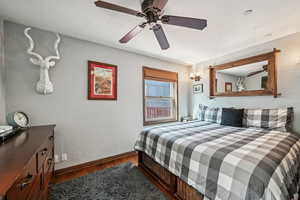 Bedroom featuring wood finished floors, baseboards, a ceiling fan, and a textured ceiling
