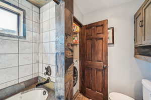 Full bathroom featuring toilet, washer / clothes dryer, and  shower combination
