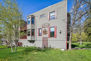Back of house featuring a balcony and a lawn