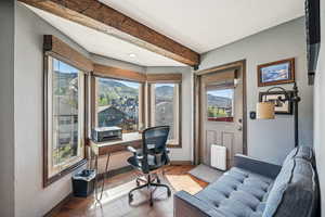 Office space featuring baseboards, hardwood / wood-style flooring, beam ceiling, and a textured wall