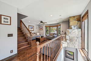 Living room with wood finished floors, a ceiling fan, recessed lighting, and stairway