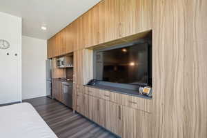 Kitchen with appliances with stainless steel finishes, dark wood finished floors, modern cabinets, and light brown cabinets