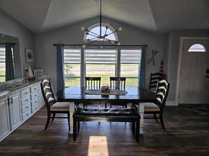 Dining space with vaulted ceiling, a chandelier, plenty of natural light, dark wood-style floors, and baseboards