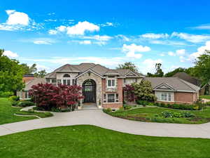 View of front of house featuring a front lawn, stone siding, stucco siding, and a tiled roof