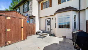 Back of property featuring stucco siding, fence, storage shed and a patio area