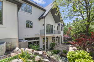 Back of house with a balcony, cooling unit, stucco siding, and a patio