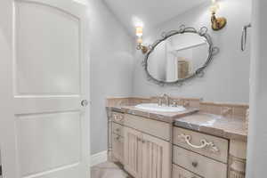Bathroom featuring vanity, baseboards, and vaulted ceiling