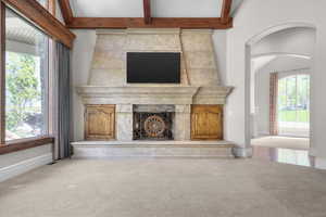 Living room with carpet floors, baseboards, arched walkways, and beam ceiling