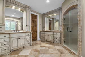 Bathroom featuring a shower stall, two vanities, stone finish flooring, recessed lighting, and baseboards