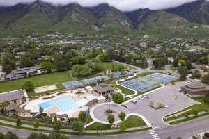 Drone / aerial view of community pool and pickleball courts with mountain background