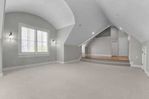 Additional living space featuring vaulted ceiling, carpet flooring, and baseboards