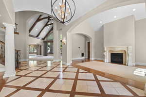 Entrance foyer with a high end fireplace, high vaulted ceiling, inlaid floor details, recessed lighting, and a chandelier