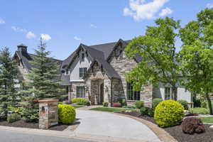 View of front of property with stone siding, a chimney, and stucco siding
