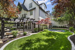 Rear view of property featuring stucco siding and a pergola