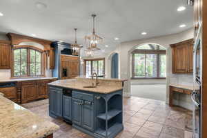 Kitchen with a sink, backsplash, baseboards, an island with sink, and recessed lighting