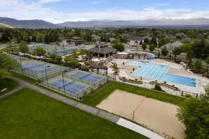Drone / aerial view of community pool and pickleball courts with valley view