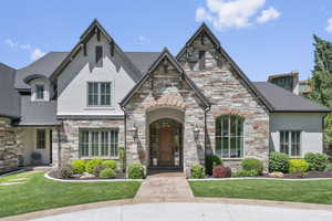 View of front of property with stucco siding, stone siding, and a front lawn
