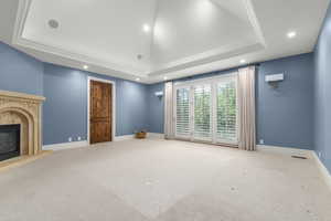 Bedroom featuring a raised ceiling, recessed lighting, carpet, and a fireplace