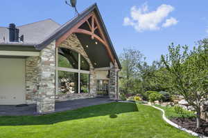 View of side of home featuring stone siding and a lawn
