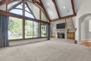 Living room featuring carpet floors, a high end fireplace, high vaulted ceiling, beamed ceiling, and baseboards