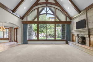 Living room featuring a chandelier, a premium fireplace, plenty of natural light, baseboards, and beamed ceiling