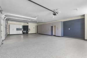 Garage featuring a garage door opener, baseboards, and a sink