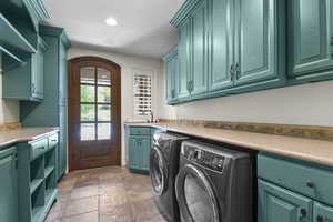 Laundry room featuring washing machine and clothes dryer, cabinet space, and recessed lighting