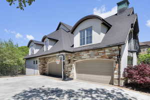 View of front of house with stone siding, concrete driveway, stucco siding, fence, and garage