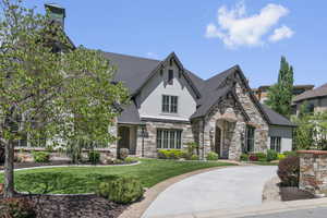 View of front of property featuring stone siding, stucco siding, and a front yard