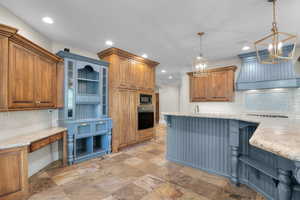 Kitchen with black appliances, stone tile floors, backsplash, recessed lighting, and a chandelier