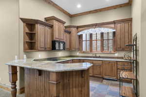 Second Kitchen featuring black appliances, a peninsula, open shelves, ornamental molding, and a sink