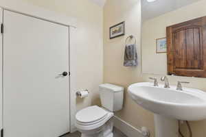 Half bath featuring toilet, a sink, and baseboards